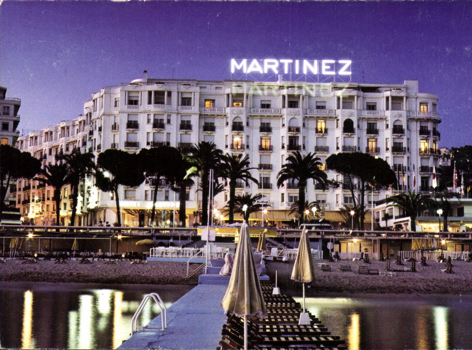 CPM Cannes Alpes Maritimes Sur la Croisette et en debut de soiree l'Hotel Martinez 